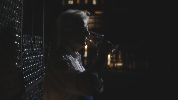 熟练的酿酒师精致地握着酒杯，深深吸入美酒的味道图片下载