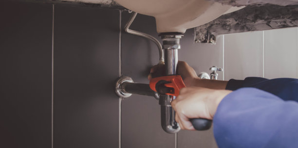 在浴室工作的水管工，管道维修服务，修理水管道泄漏，更换厨房水槽排水管图片下载