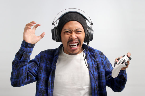 愤怒的亚洲玩家正在用手柄玩电子游戏图片下载