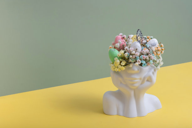 石膏头像雕像，上面有复活节彩蛋和鲜花。复活节创意理念图片下载