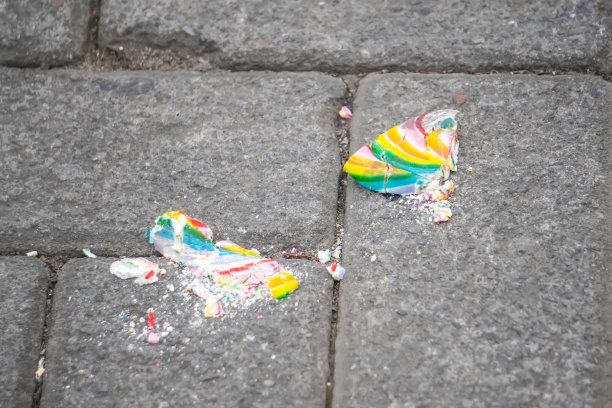 一个五彩缤纷的棒棒糖，掉在地上踩碎了。心碎的概念，信任问题，心理障碍，精神疾病。图片下载