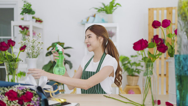 美丽的亚洲女花师在花店里给花喷水，给花增加水分和活力，防止花在花店里枯萎。花店概念，小企业主图片下载