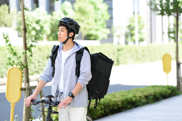 年轻的亚洲男子背着背包，骑着自行车提供送货服务图片下载