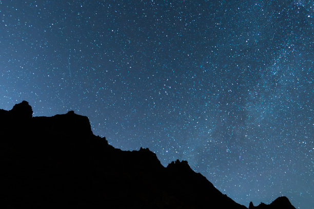 在欧洲西班牙加那利群岛特内里费岛泰德国家公园拍摄的一张美丽的夜景照片，天空中布满了星星，银河系的一部分与岩石山的剪影图片下载