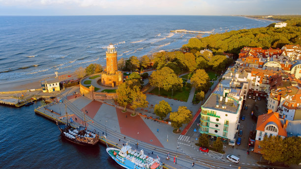 无人机拍摄的照片捕捉到了科洛布热格的海洋魅力，包括标志性的灯塔、蔚蓝的大海、汹涌的海浪、远处的码头和树上的秋色。图片下载