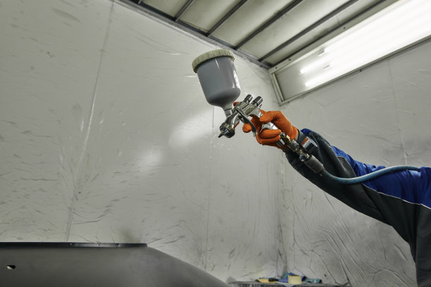 这张照片拍摄了一个汽车车间的场景，展示了油漆各种汽车零件的过程。汽车的不同部件汽车的引擎盖，保险杠，更小的细节。图片下载