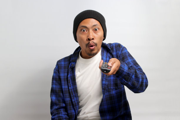 一个亚洲人拿着电视遥控器图片下载