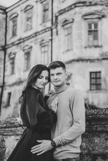 豪华夫妇附近的老皮赫特西城堡。新娘拥抱新郎。女人和男人在街上的墙。日落时分，身穿长裙的女子和男子在古代宫殿附近的楼梯上散步。黑色和新郎新婚夫妇的照片。图片下载