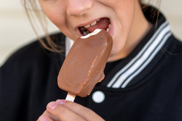 一个可爱的小女孩拿着巧克力冰棒棒的肖像。图片下载