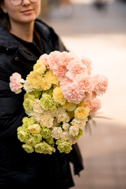 女人手里拿着一大束不同颜色的康乃馨。假日礼物图片下载