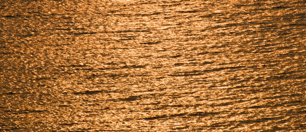 太阳光线在海面上的反射。金色的背景。宽的照片。图片下载