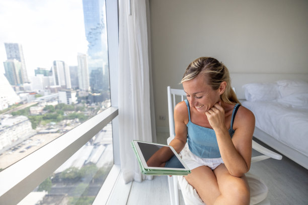 一个女人在酒店房间里用平板电脑图片下载