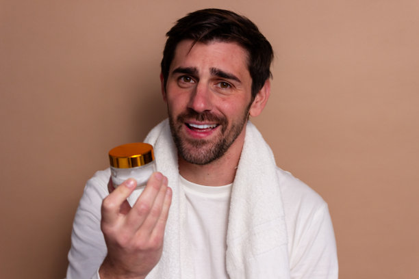 蓄着胡子的英俊年轻人手持一瓶乳液的画像图片下载