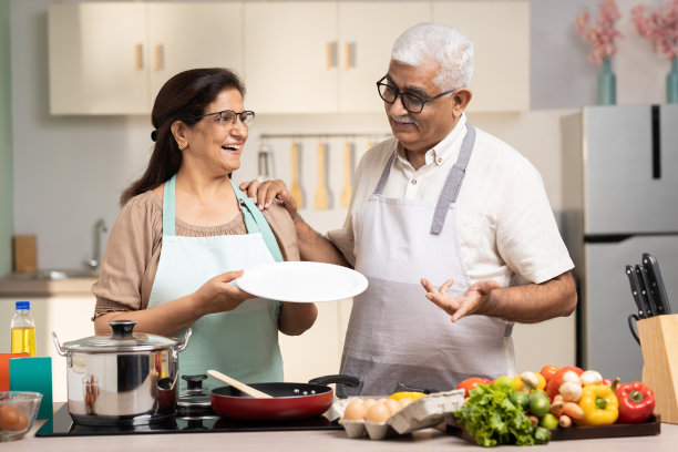 幸福的老年夫妇在家里一起做饭时展示饭菜，库存照片图片下载