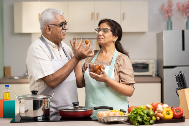 幸福的老年夫妇在家里一起做饭时分享甜食，库存照片图片下载