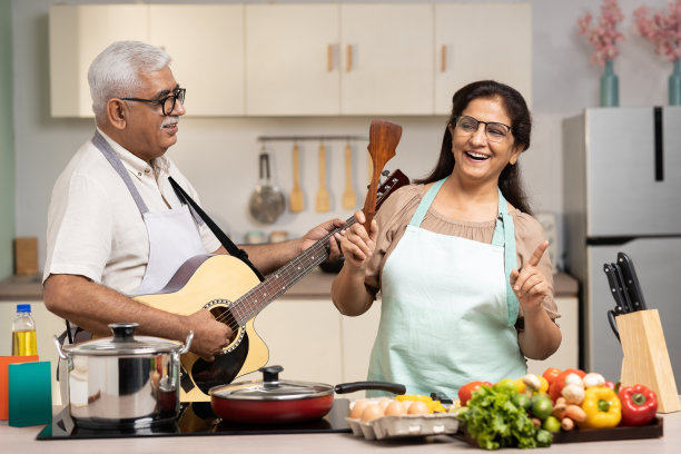 幸福的老年夫妇弹吉他，在家里一起做饭，股票照片图片下载