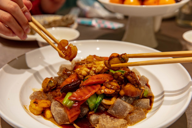 筷子夹起中国炒制的海鲜，包括虾、扇贝和鱿鱼图片下载