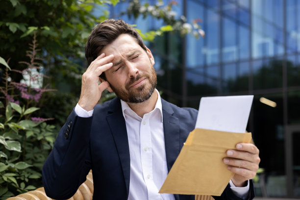 一个震惊的年轻商人的特写照片，他在外面的街道上，收到了坏消息的信，悲伤地闭上眼睛，抱着头图片下载