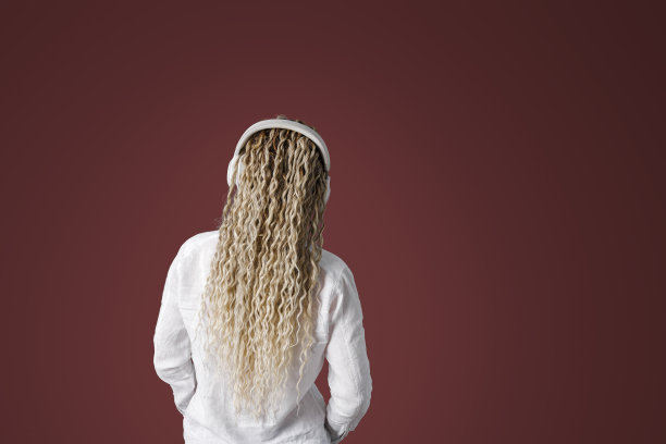 现代时尚的女少女头戴耳机，听歌跳舞，金色长卷发，后视，红棕色背景配上复制空间，极简的生活方式无脸潮流图片下载