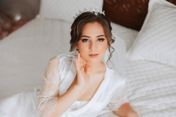 一位美丽的黑发新娘，头上戴着头饰，穿着漂亮的睡袍，准备参加婚礼。特写婚纱照，照片。图片下载