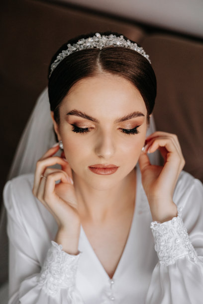 一位美丽的黑发新娘，头上戴着头饰，穿着漂亮的睡袍，准备参加婚礼。特写婚纱照，照片。图片下载