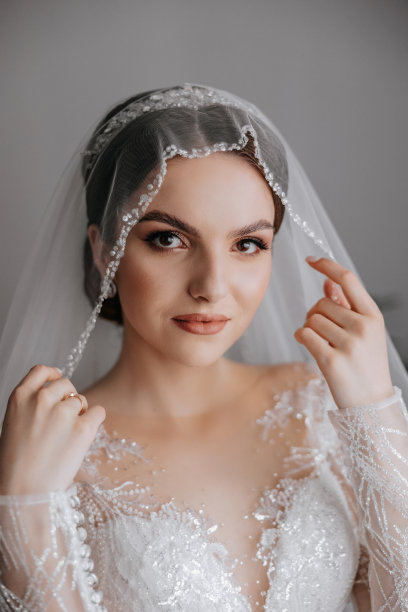 婚礼的早晨，一位美丽的新娘穿着优雅的婚纱，一头黑发，化着迷人的妆，在房间里拍摄的时尚照片。新娘正在为婚礼做准备图片下载