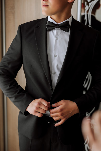 那人把纽扣扣在夹克上。新郎正在为婚礼做准备。手的详细特写照片图片下载