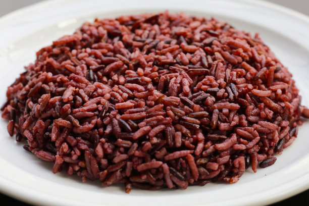 煮熟的黑莓米饭在白色盘子在黑暗的背景。图片下载