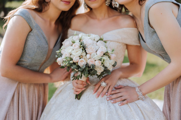 新娘的女朋友。新娘手持花束，特写照片。大自然中的婚礼。女孩们穿着相同的衣服。图片下载