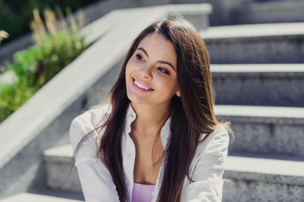 照片宁静可爱的女孩牙齿微笑坐在楼梯看着感兴趣的远远头脑风暴的自由时间和谐的街道外面图片下载