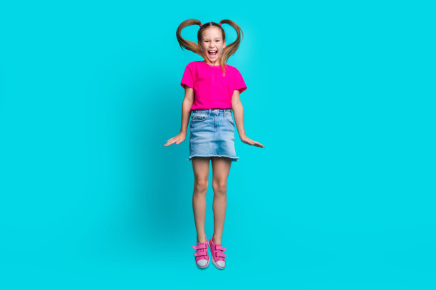 在蓝绿色的背景下，穿着时尚的t恤牛仔裙尖叫跳跃的女生全身照片图片下载