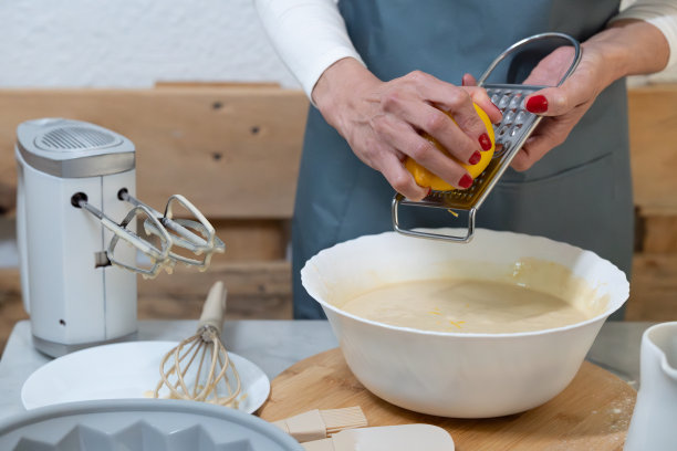 一个女人正在做甜点，她正在用磨碎器磨柠檬。图片下载