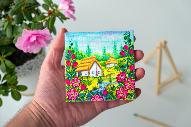 一张乌克兰村庄的照片被拿在手掌上，背景是一个花瓶。装饰艺术。彼得里基夫卡画静物画。图片下载