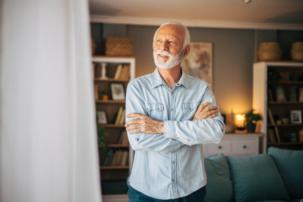 英俊活泼的老人站在窗边，双臂交叉图片下载
