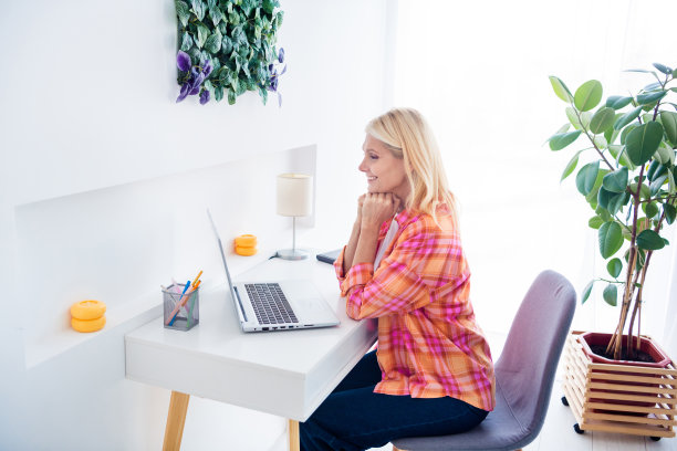 照片积极的老太太坐在桌子上看电影，工作从上网本在家庭日光公寓网络研讨会图片下载