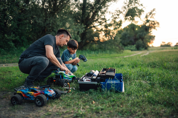 一个儿子和他的父亲在大自然中修理玩具车的照片。图片下载