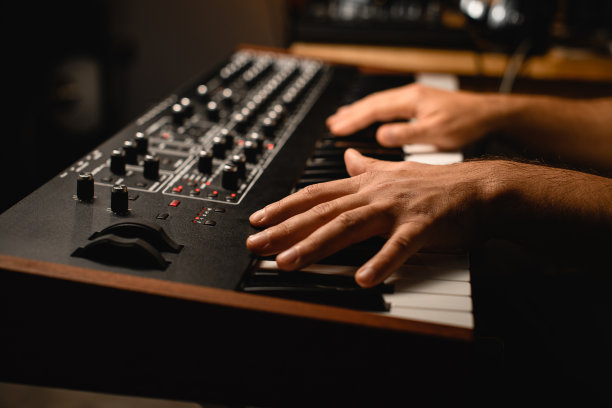 在录音室里，一个音乐家在模糊的背景上演奏合成器图片下载