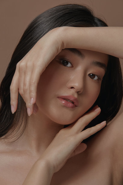 亚洲女性的肖像，干净健康的皮肤，在米色背景下，双手紧贴脸，垂直特写照片图片下载