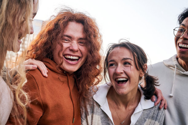 四名年轻学生大声笑的照片。朋友们一起微笑，一起玩乐。图片下载