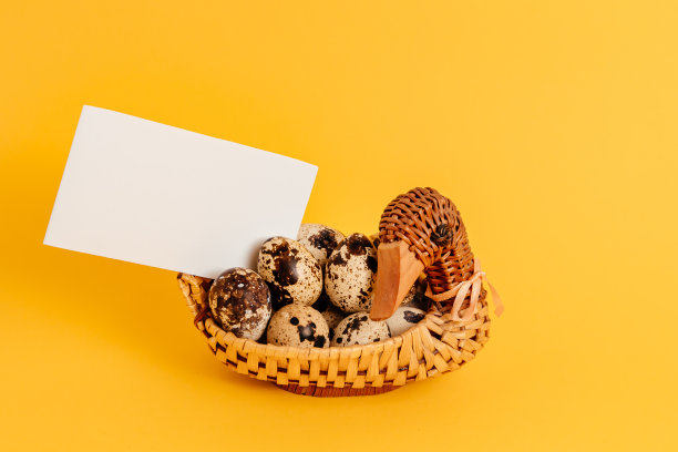 复活节假期模型设计。手工鸭形稻草篮子与大理石鹌鹑蛋在黄色背景。室内装饰。健康的有机食品。的名片。纸请注意。空的地方留言图片下载