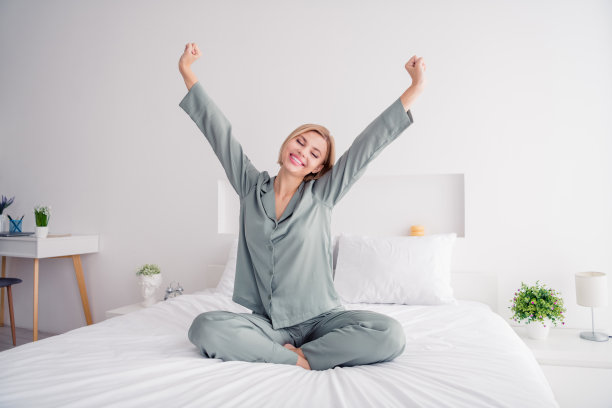 年轻的金发甜美可爱的女士的照片灰色的睡衣在公寓寒冷举起拳头在酒店卧室醒来白光室内图片下载