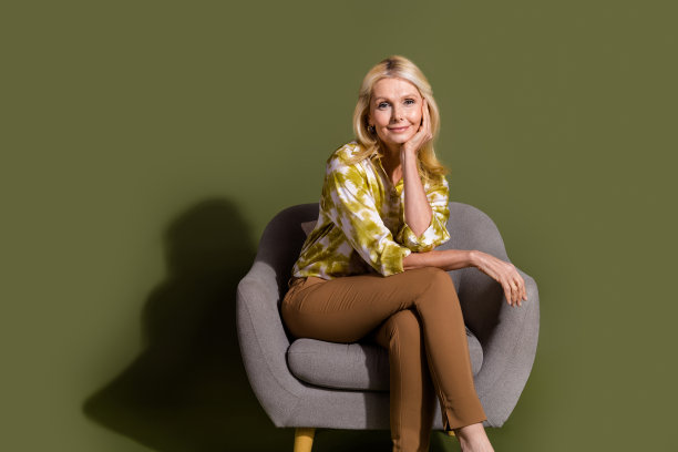 女性招聘人员的全身照片，坐在扶手椅上，触摸脸颊，倾听你的工作经历，孤立的卡其色背景图片下载