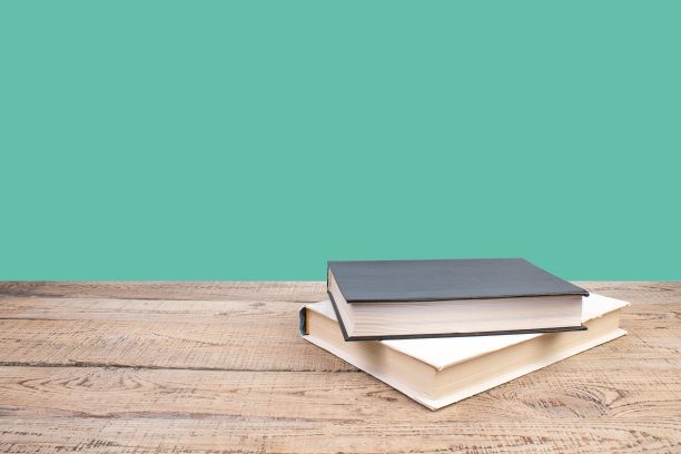 组成与精装书，扇页在木制甲板桌和绿色背景。书堆积。回到学校。副本的空间。教育背景。图片下载