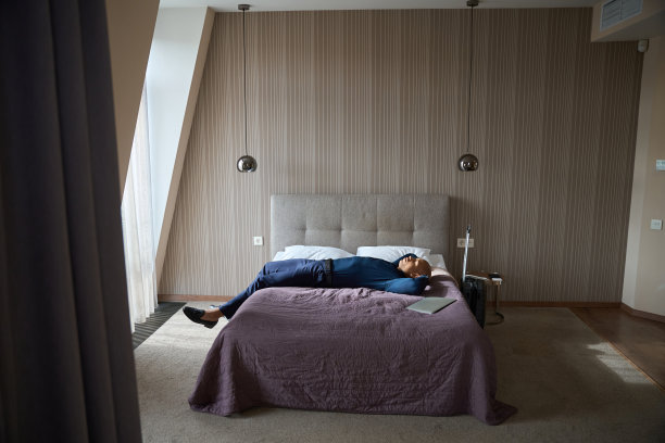 疲倦的非裔美国男性企业家躺在床上休息的侧视图图片下载