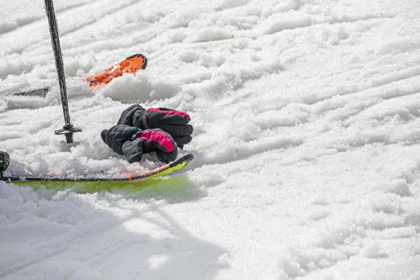 在阳光明媚的日子里，在斜坡上的湿雪上戴着手套滑雪。休闲图片下载