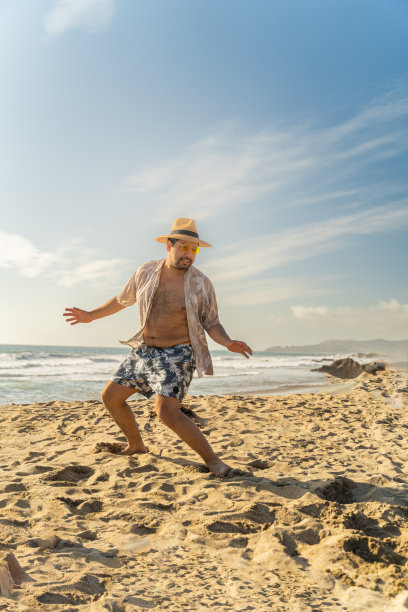 一个年轻的西班牙裔男性在海滩上快乐地摆姿势的垂直照片图片下载