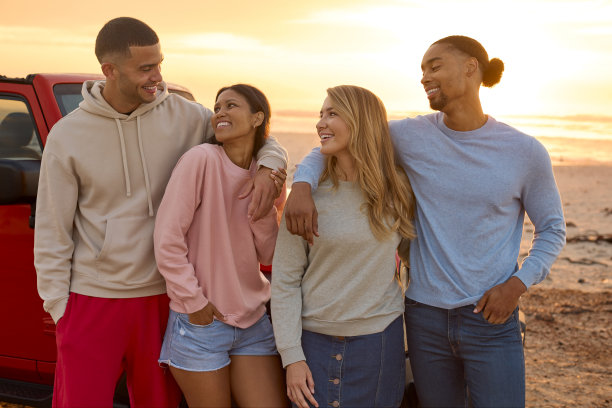 一对夫妇和朋友一起站在沙滩上看日出的照片图片下载