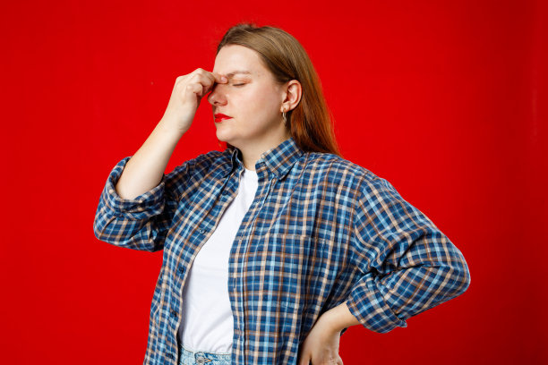 年轻美丽的30多岁女子头痛，孤立在红色背景上。饱受偏头痛折磨的疲惫女孩肖像。手放在头上。图片下载