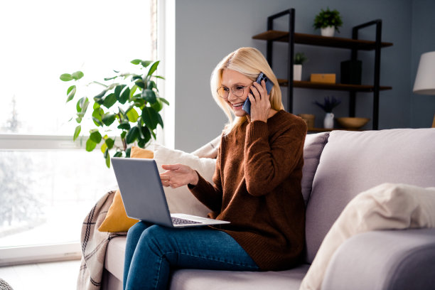 开朗的成熟女人坐在沙发上讲电话讨论项目计划合同舒适的室内工作空间的照片图片下载