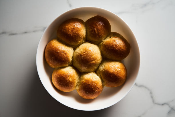 在圆形烤盘中放入汉堡包或迷你包。非常柔软的新鲜出炉的自制，涂了黄油。白色大理石背景。简约的照片。俯视图图片下载